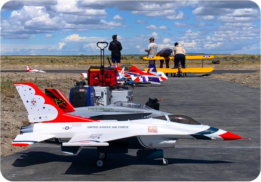 RC airplanes on the tarmac/runway while pilots prepare in the background